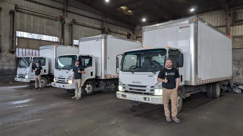 Junk Raider crew members standing with three Junk Raider box trucks