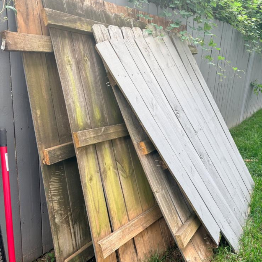 Old wooden fence panels removed and stacked by Junk Raider fence removal crew in Charlotte