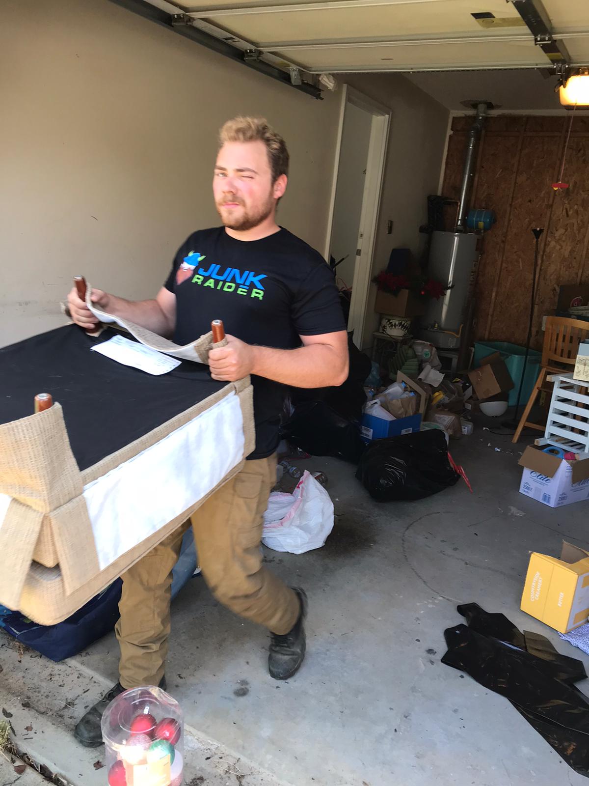 Junk Raider crew member carrying furniture out during a garage cleanout